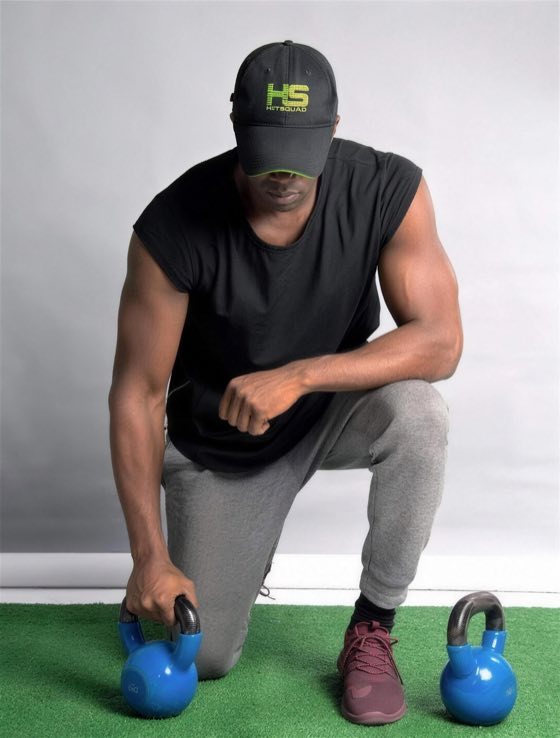 Maje Ayida, founder of Eden Wellness, kneeling beside two kettlebells